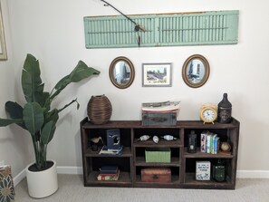 Una consola de madera con varios objetos decorativos, una planta en maceta y espejos fijos a la pared.