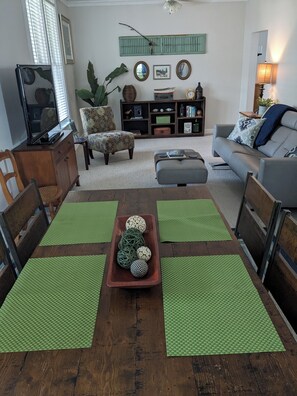 Un comedor con una mesa de madera, individuales verdes y un cuenco decorativo en el centro.