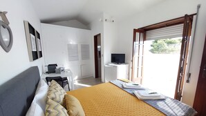 Une chambre à coucher comprenant un lit, un bureau, une télévision et une armoire.