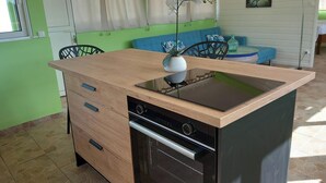 A compact kitchen with a wooden countertop, integrated oven, and a dining area with a blue sofa and chairs. - Atypical cottage ideally located for visiting the whole of Martinique.  (Rivière-Salée)