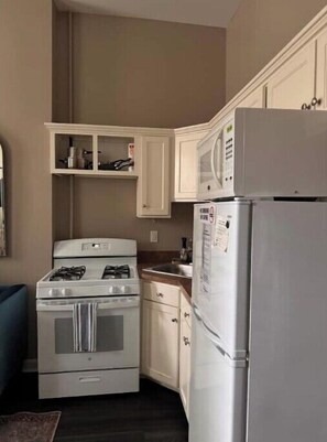 Kitchen area with a gas stove, oven, refrigerator, and microwave.