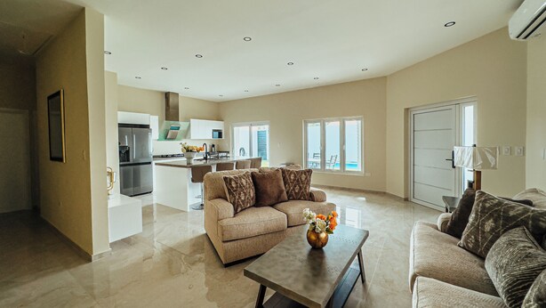 A spacious living area with a modern kitchen, a large sofa set, and a dining area. - Your second home in Aruba (Oranjestad)