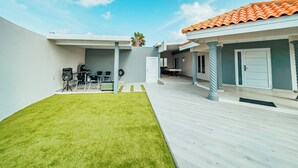 A modern house with a patio, a lawn, and a tiled roof. - Your second home in Aruba (Oranjestad)