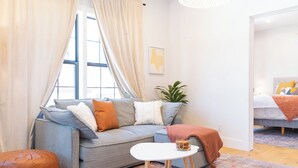 A modern living room with a grey sofa, a small white table, and a colorful rug.