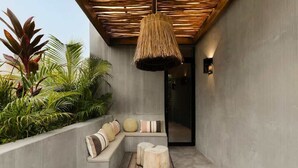 A modern outdoor seating area with a concrete bench, a woven ceiling light, and tropical plants. - Casa Kutzi Kutzi Paradise Villa Beach Club Access (Tulum)