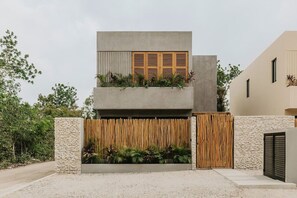 Stunning two-story building with a minimalist design, set amidst lush greenery and a natural landscape.