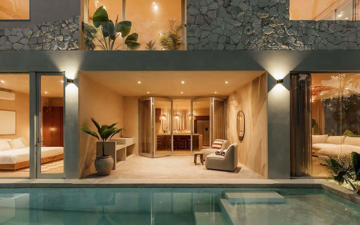 Una casa moderna de dos pisos con piscina, comedor y sala de estar con sofá y mesa de centro.
