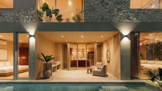 Una casa moderna de dos pisos con piscina, comedor y sala de estar con sofá y mesa de centro.