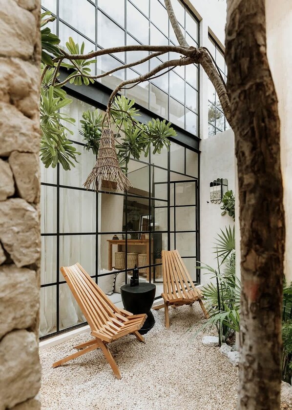 Ein modernes Interieur mit einer Glasschrankwand, Holzstühlen, einem Hängekorbstuhl und Zimmerpflanzen.