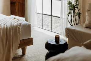 A bedroom with a bed, bedside table, and a window with a view.