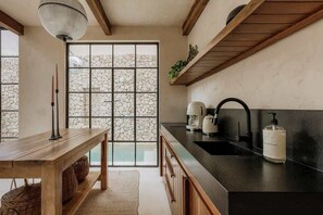 Eine Küche mit Steinwand, Holzschränken, einer schwarzen Arbeitsplatte und einem Fenster mit Steinmuster.