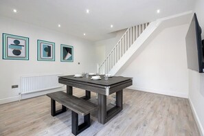 Un espace repas moderne avec une table, un banc et une œuvre d’art encadrée accrochée au mur.