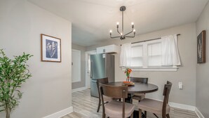 A dining area with a round table, four chairs, a chandelier, and a potted plant. - Game Room + Fenced Yard - King Bed - Pet Friendly (Wichita)