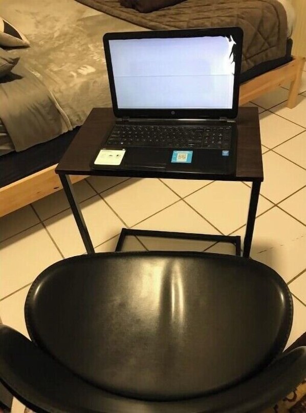 Work in comfort with a laptop and desk space, featuring a bed in the background.