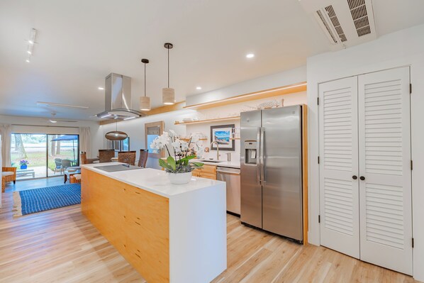 Una cocina moderna con una isla central, electrodomésticos de acero inoxidable y vistas al exterior.