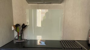 A kitchen with a stainless steel range hood, a black countertop, and white cabinetry. - T2 vacation home in Sorède, near Argeles, with swimming pool and private parking (Sorède)