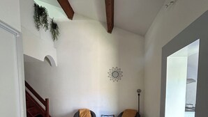 A spacious room with a wooden dining table, white chairs, and a staircase leading to another area. - T2 vacation home in Sorède, near Argeles, with swimming pool and private parking (Sorède)