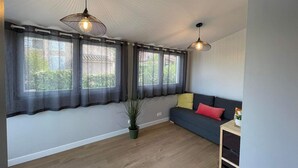A modern living room with a sofa, a potted plant, and two pendant lights. - T2 vacation home in Sorède, near Argeles, with swimming pool and private parking (Sorède)