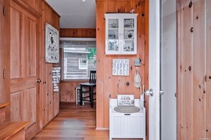 A wooden interior hallway with a dining area, a cabinet with glass doors, and a sign on the wall.