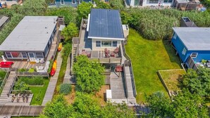 Un barrio residencial con una casa que tiene una terraza, un jardín pequeño y una vista despejada del vecindario.