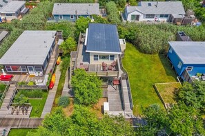 A residential area with a house featuring a deck, a small garden, and a clear view of the surrounding neighborhood. - Charming Fair Harbor 3br steps to ocean, sunset view, WiFi, A/C, outdoor shower. (Bay Shore)