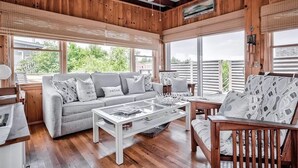 Un salón acogedor con un sofá gris, una mesa de centro de madera y un sillón estampado.