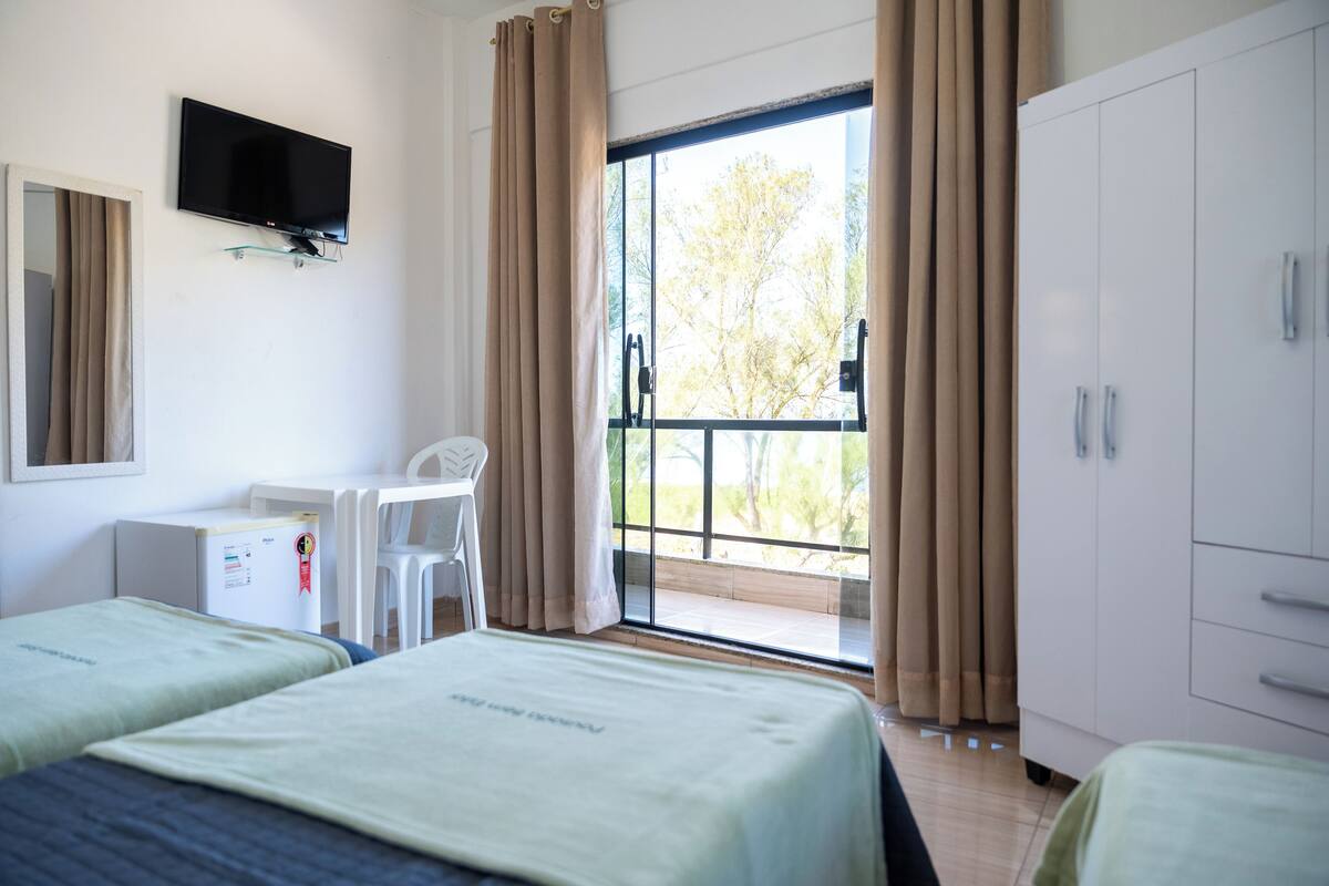 Een hotelkamer met twee bedden, een bureau, een stoel, een televisie en een kledingkast.