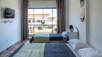 Habitación de hotel con dos camas, televisión y ventana con cortinas.