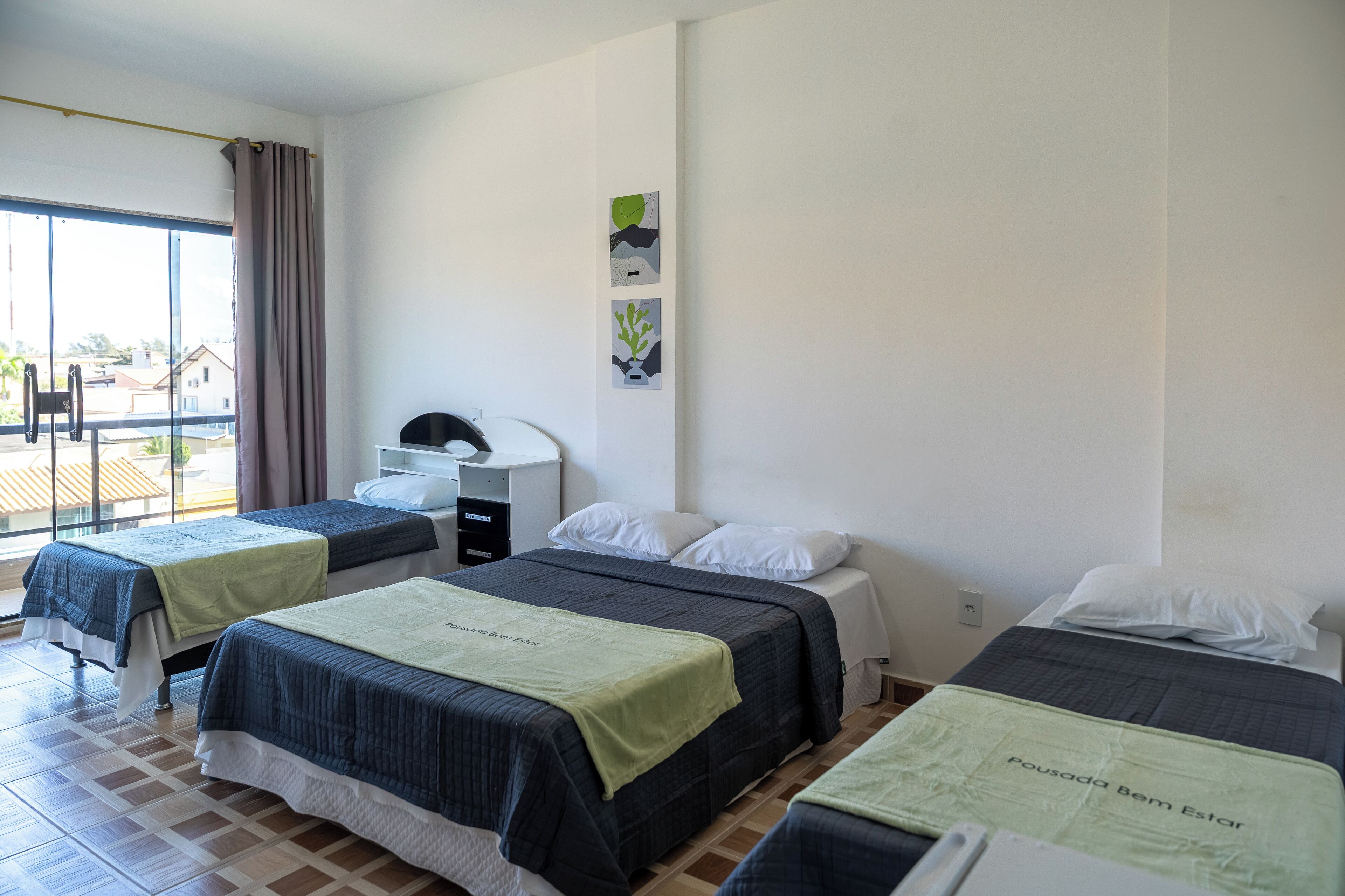 A hotel room with two beds, a desk, and a window with curtains.