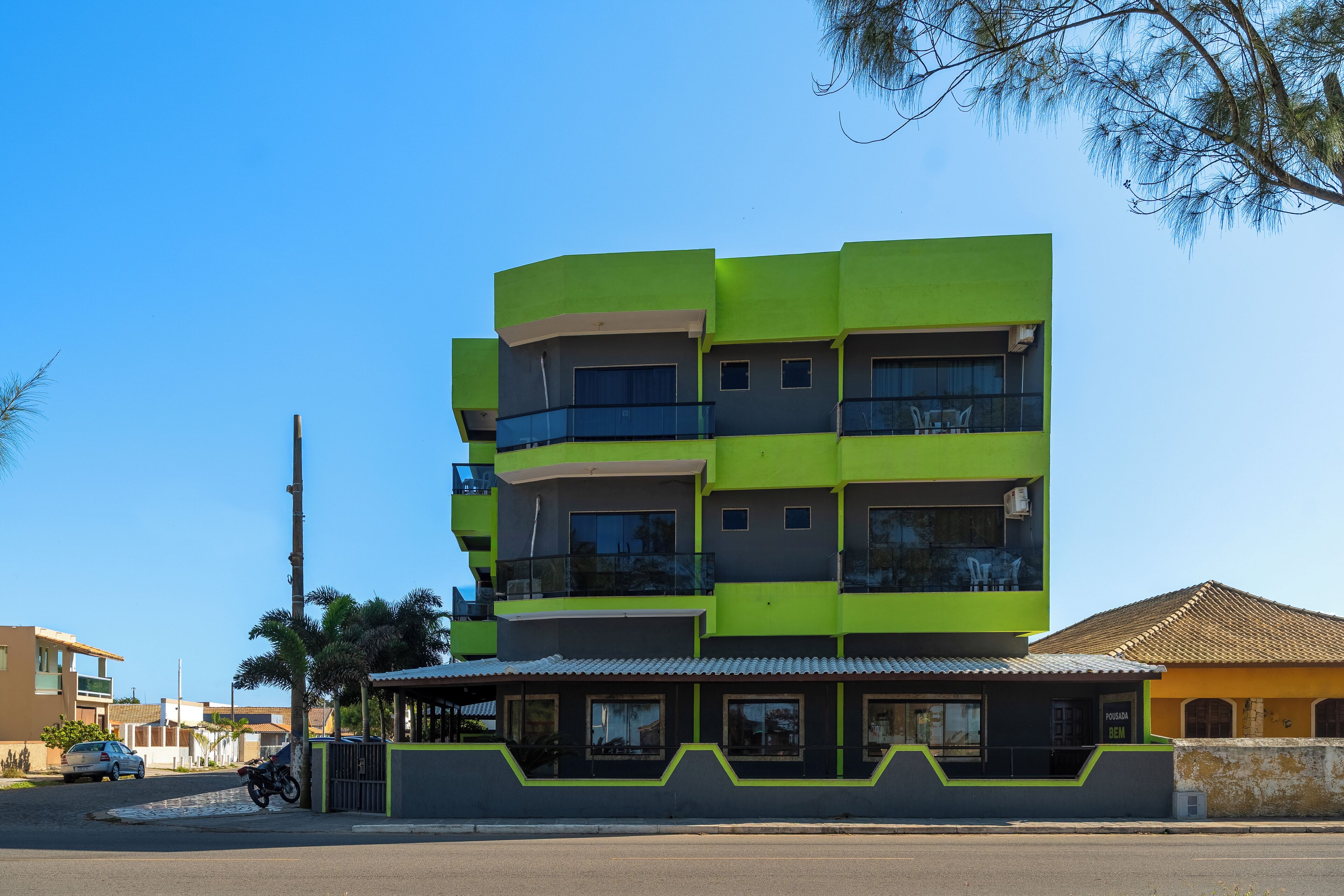 A multi-story building with balconies, a covered entrance, and a visible restaurant sign.