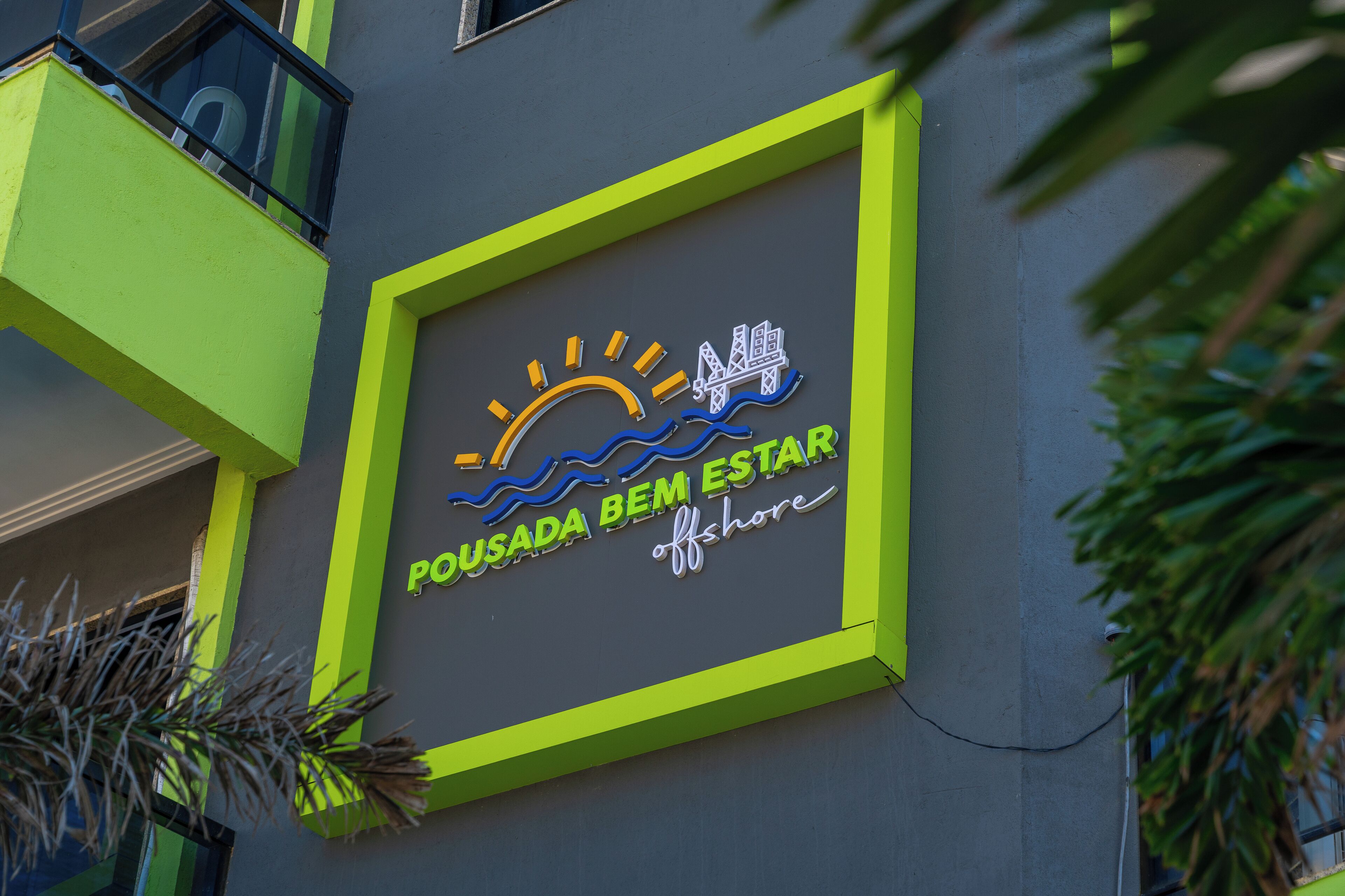 A building with a neon sign that reads "POUSADA BEM ESTAR offshore."