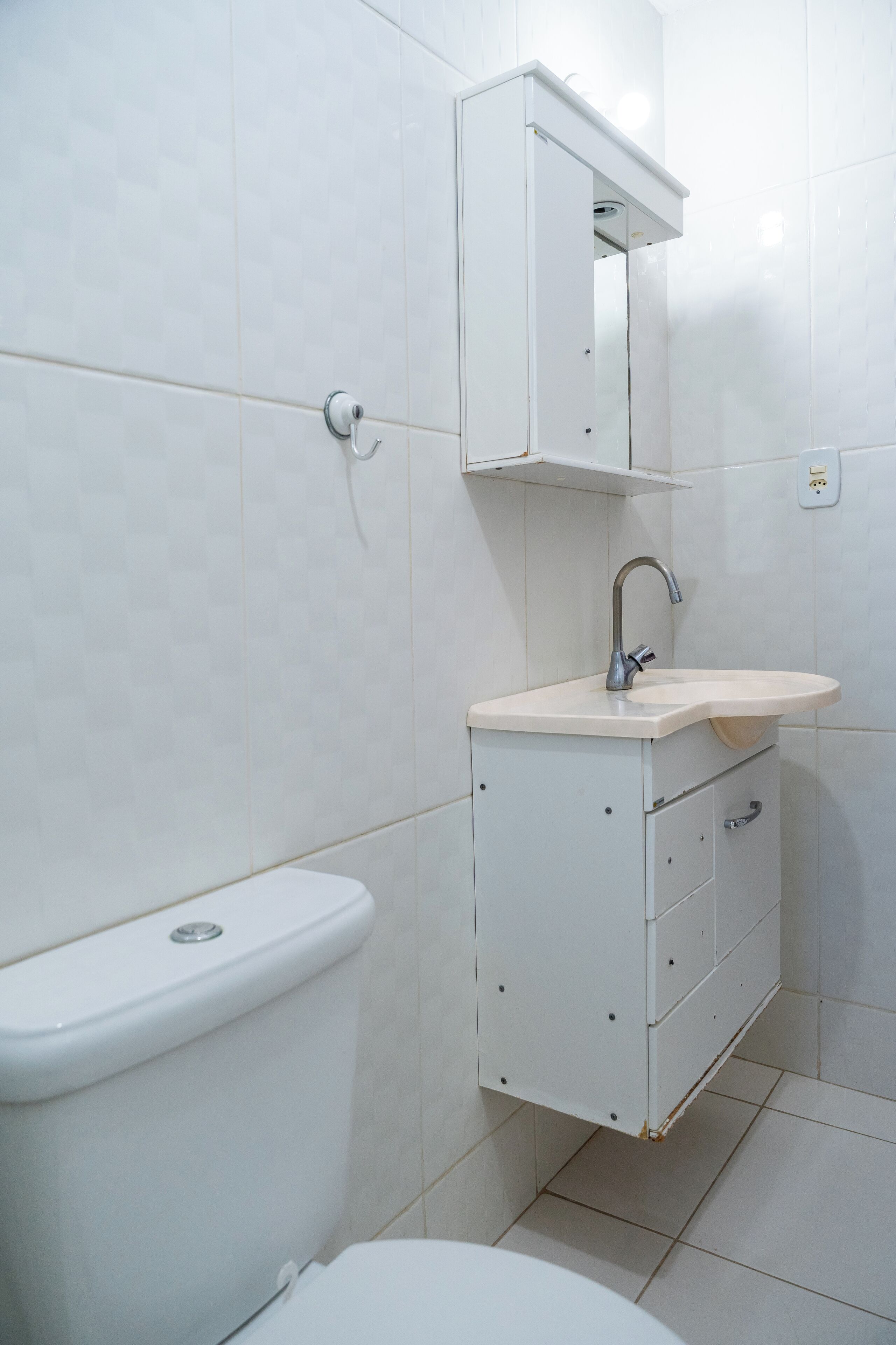A bathroom with a white toilet, a sink with a mirror above it, and a cabinet below.