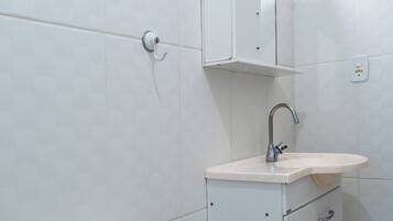A bathroom with a white toilet, a sink with a mirror above it, and a cabinet below.