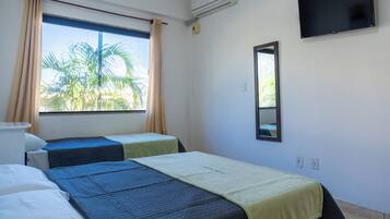 Quarto de hotel com duas camas, uma televisão e uma janela com cortinas.