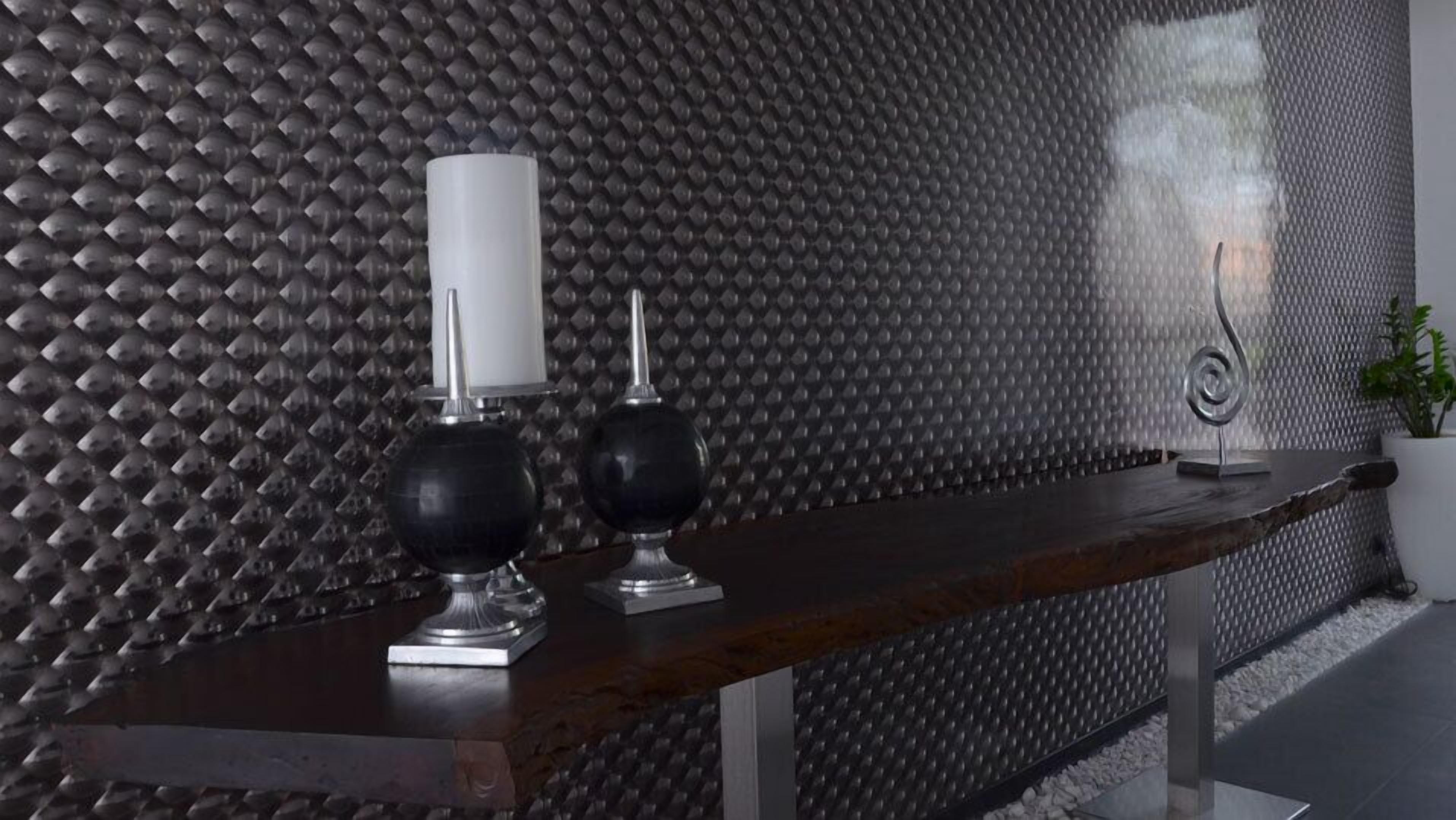 Un interior moderno con una pared texturizada, un banco de madera y dos candelabros.