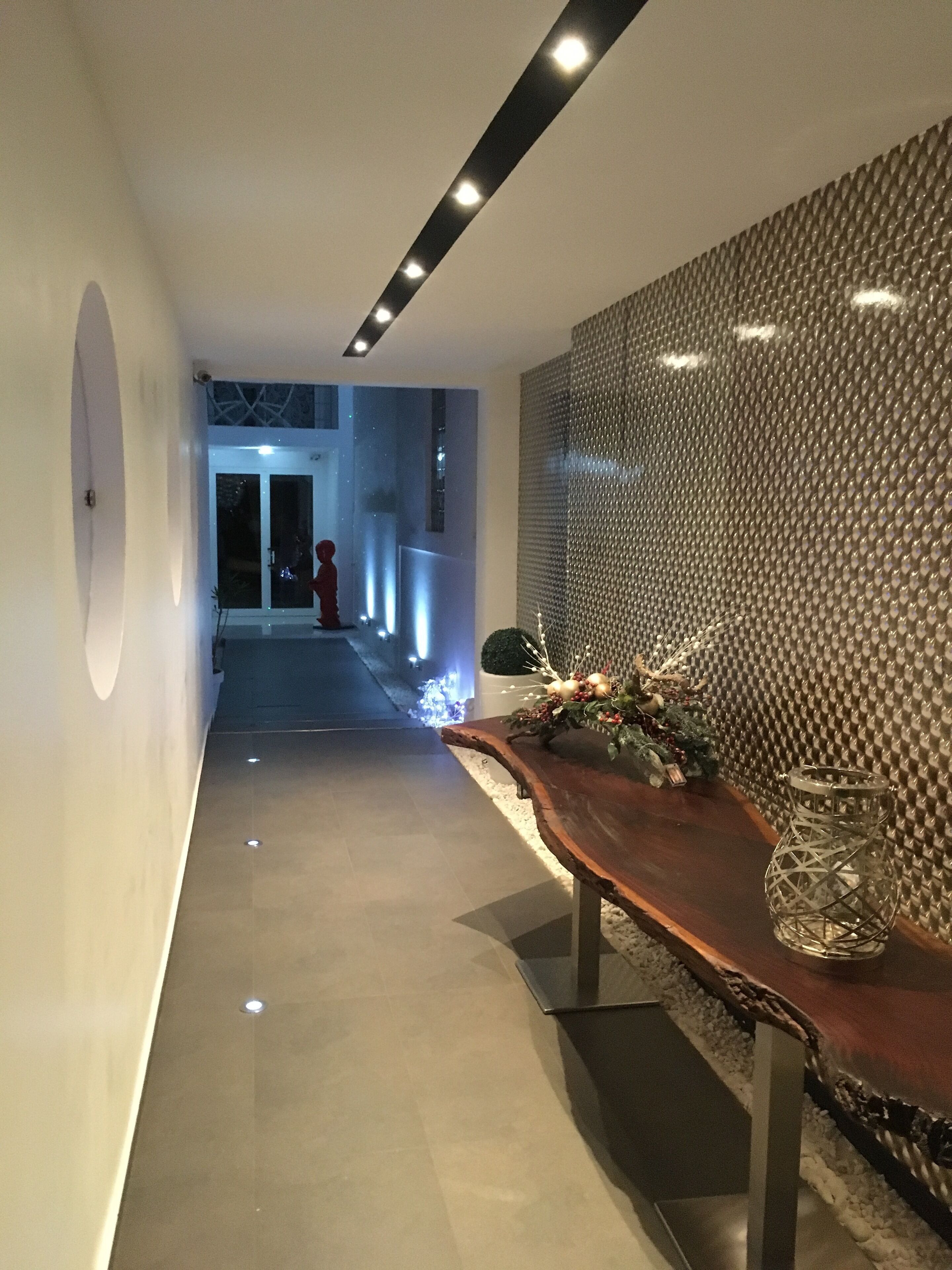 A modern hallway with a wooden bench, a textured wall, and a glass door at the end.