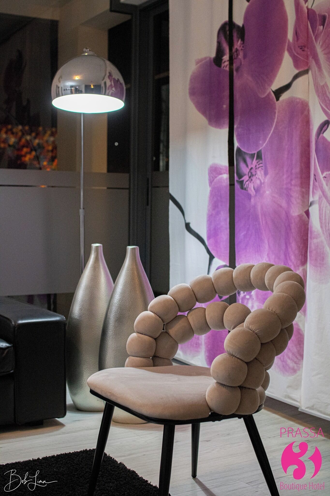 Una habitación moderna con una silla esférica singular, una lámpara de pie y un cuadro grande con motivos florales.