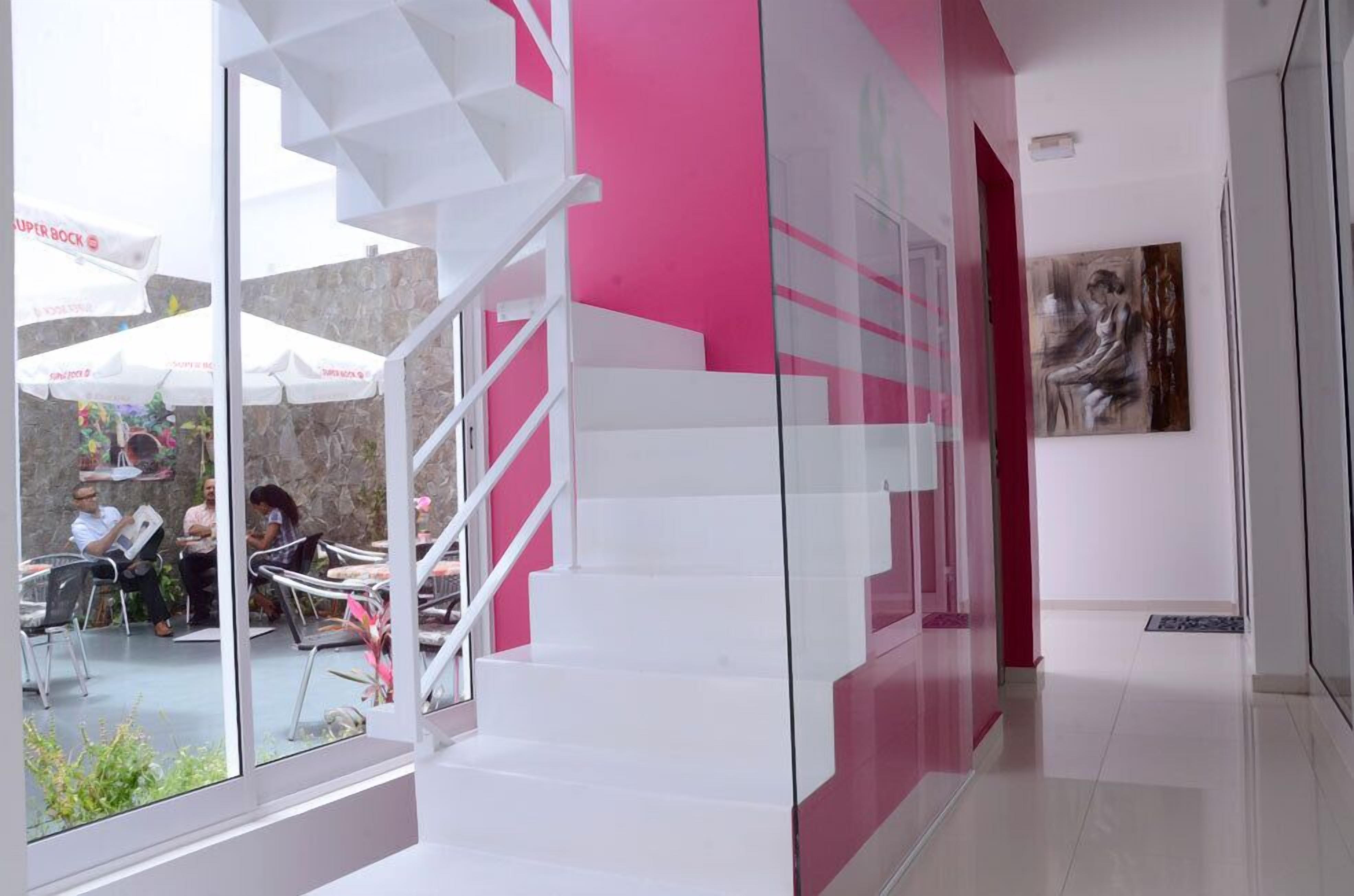 A modern interior with a staircase, a glass wall, and a dining area with outdoor seating.