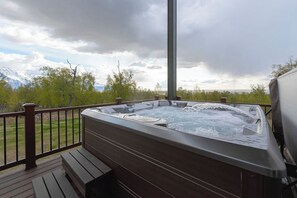 Ein Whirlpool auf einer Holzterrasse mit Blick auf Berge und Bäume.