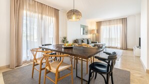 A modern dining area with a wooden table, chairs, and a hanging light fixture.