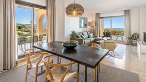 A spacious living area with a large dining table, comfortable seating, and a view of the outdoors.