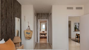Et moderne hotelværelse med en stor seng, en sengebordlampe, et spejl og udsigt til badeværelset.