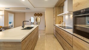 Una cocina moderna con una isla grande, armarios de madera y electrodomésticos integrados.