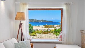 Una habitación con vista a la playa y al mar, una lámpara y una cama con almohadas.