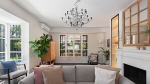A modern living room with a grey sofa, a large plant, and a fireplace.