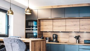 A modern kitchen with wooden cabinets, a bar area, and a seating space. - Chalet Amadeus - Designer Luxury Chalet for 14 (Piesendorf)