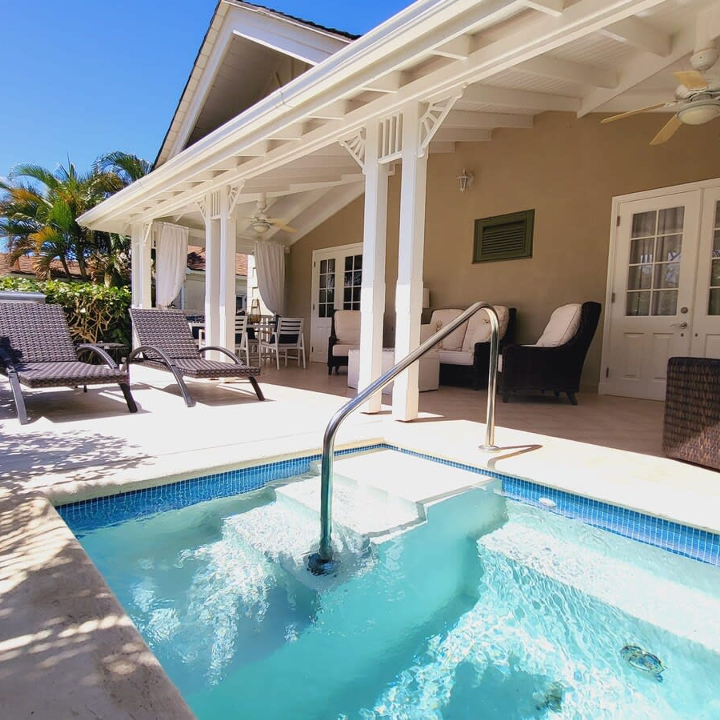 A pool area with lounge chairs, a covered patio, and a door with glass panels.