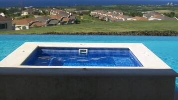 A swimming pool with a view of houses and the ocean.