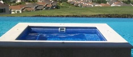 A swimming pool with a view of houses and the ocean.