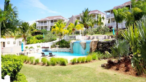 A resort with a swimming pool, lounge chairs, and a waterfall feature. - Villa Vuemont - Peaceful 3 Bedroom Villa With Pool (Speightstown)